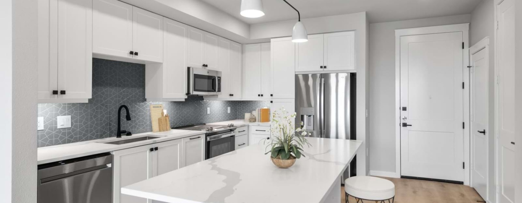 Model kitchen at our apartments in Plano, TX, featuring a kitchen island and stainless steel appliances.